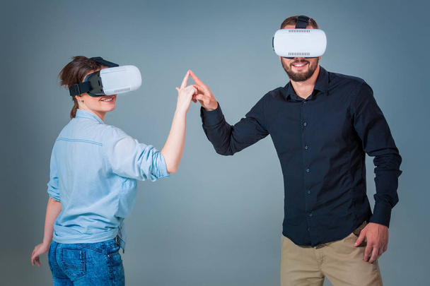 Молода пара використовує гарнітури VR на сірому фоні
 - Фото, зображення