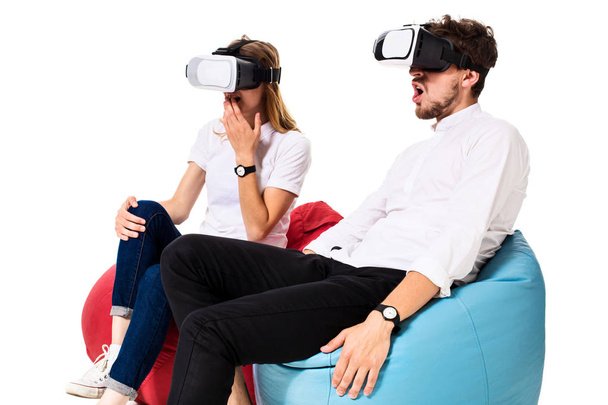 Izgatott fiatal pár tapasztalják beanbags elszigetelt fehér background ülő virtuális valóság - Fotó, kép