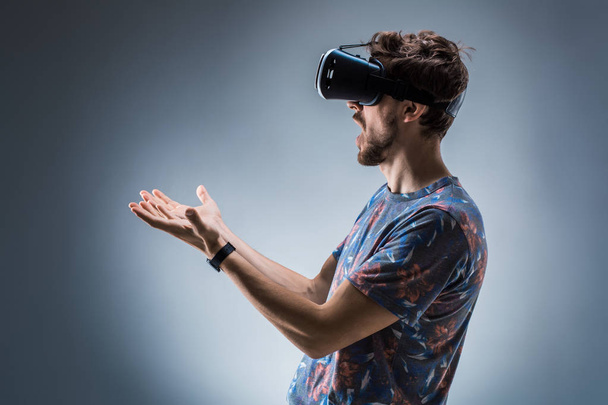 Πλαϊνή όψη, ένας νεαρός άντρας, χρησιμοποιώντας μια συσκευή VR. Συναισθήματα - Φωτογραφία, εικόνα