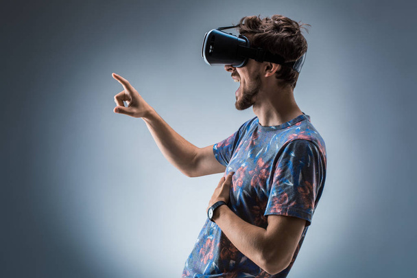 Вид збоку молодого хлопця з гарнітурою VR. Емоції
 - Фото, зображення