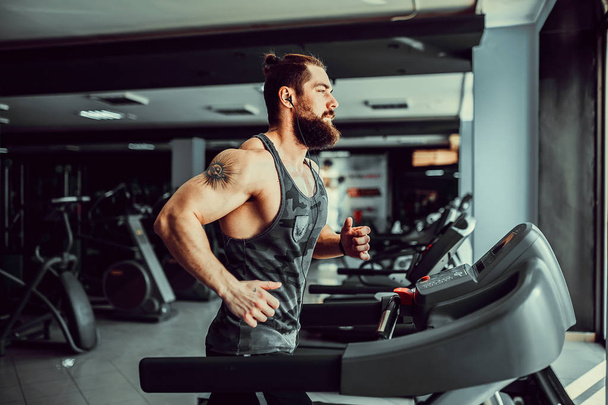Muscle man running on treadmill. - Valokuva, kuva