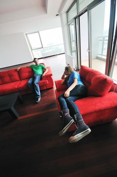 Happy couple relaxing on red sofa - Фото, зображення
