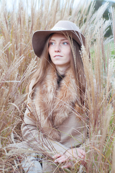 Femme en manteau de fourrure beige dans le champ sec d'automne
 - Photo, image