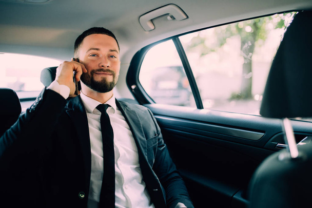 Handsome Businessman working in the backseat of a car - Photo, image