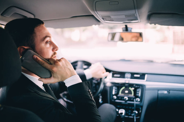 Látszó-on mozgatható telefon-egy autó vezetés közben üzletember. - Fotó, kép