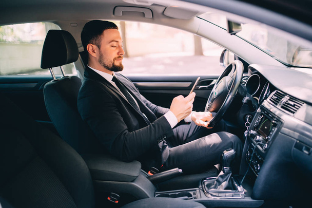 Retrato de homem de negócios bonito usar telefone no carro enquanto dirige
 - Foto, Imagem