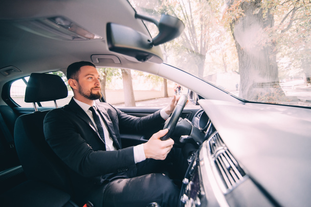 Handsome bearded Businessman driving a car on the road - Фото, изображение