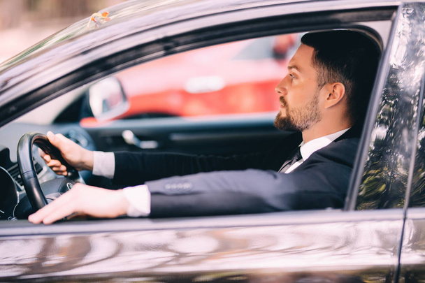 Portrait of young businessman driving a car - Photo, Image