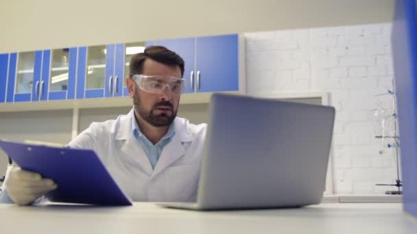 Concentrated scientist working with documents and typing - Imágenes, Vídeo