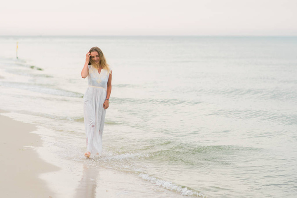 lifestyle woman standing in a white dress on the ocean coast horizontal image - Fotó, kép