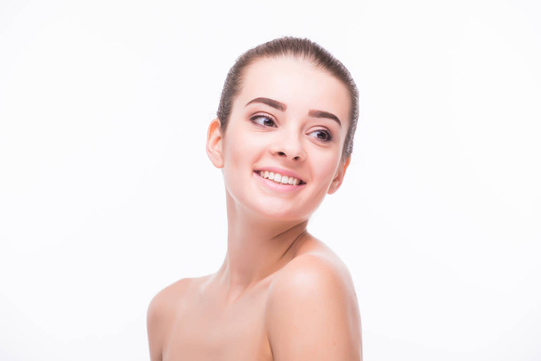 Pretty girl with big eyes and dark eyebrows, with naked shoulders, looking at camera and smiling, a model with light nude make-up, white studio background, beauty photo, copy space, close up. - Foto, immagini