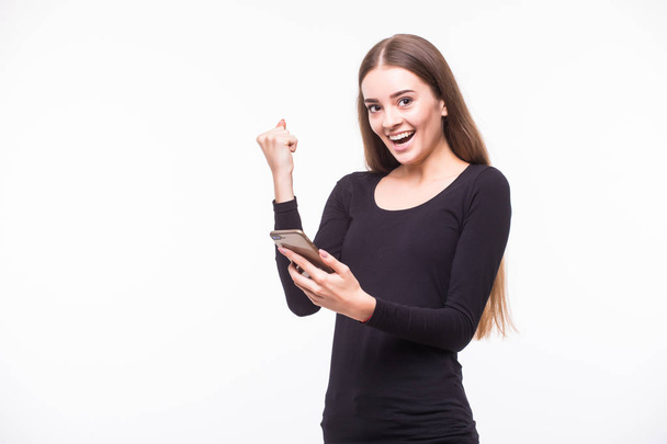 Jonge gelukkige vrouw opgewonden met smartphone. Geïsoleerde witte achtergrond. - Foto, afbeelding