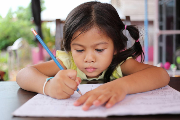 Menina asiática uso Lápis escrever letras no livro
. - Foto, Imagem