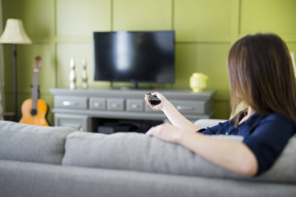 Beautiful woman watching TV sitting on couch at home - Valokuva, kuva
