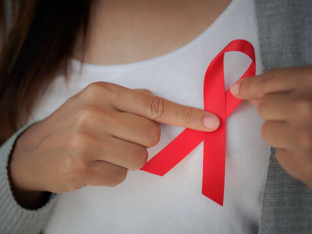 Zbliżenie kobieta ręka gospodarstwa czerwoną wstążką Hiv, Światowy dzień Aids  - Zdjęcie, obraz