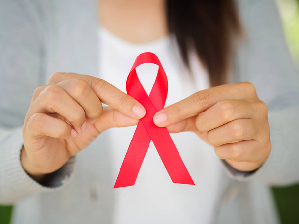 Woman hand holding red ribbon HIV, world AIDS day awareness  - Valokuva, kuva