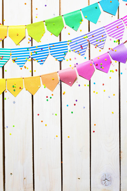 Colored flags garland. The background is white wood. - 写真・画像