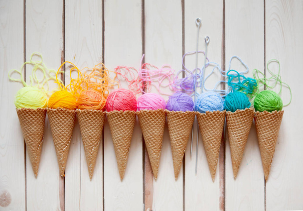 Balls of yarn lie in a waffle cone for ice cream. Coloured wool. - Фото, изображение