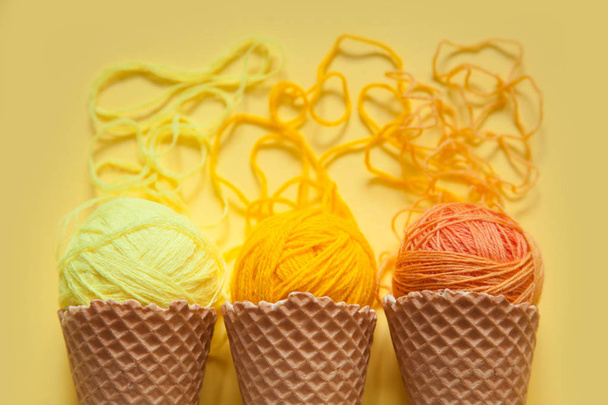 Balls of yarn lie in a waffle cone for ice cream. Coloured wool. - 写真・画像