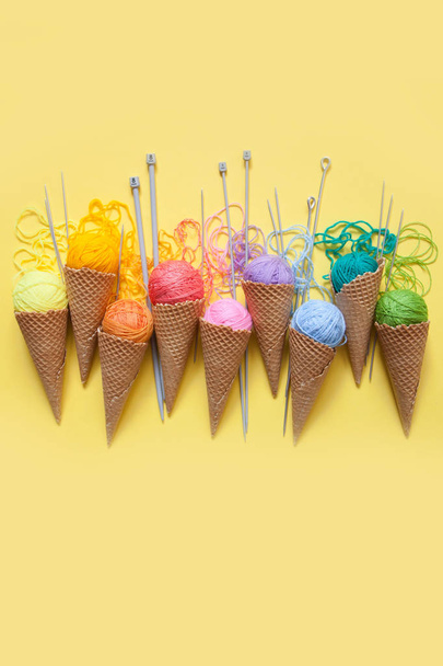 Balls of yarn lie in a waffle cone for ice cream. Coloured wool. - Foto, afbeelding