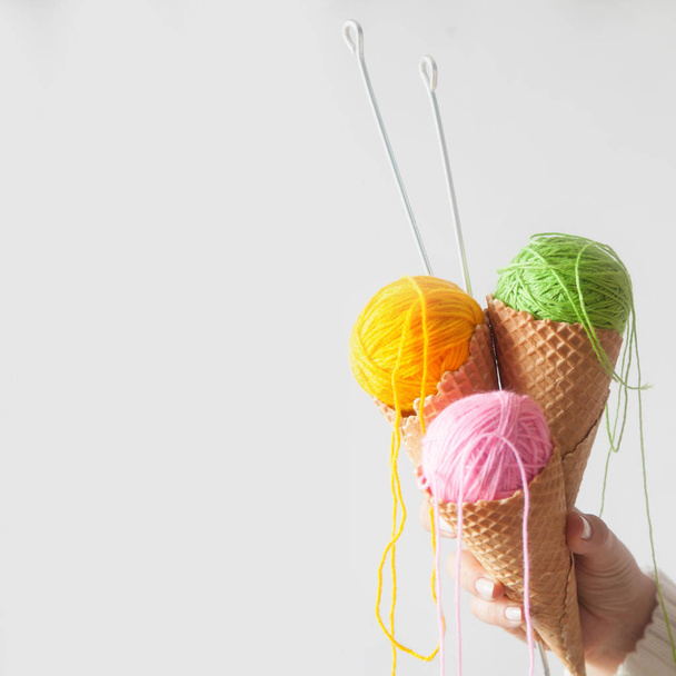 Balls of yarn lie in a waffle cone for ice cream. Coloured wool. - Фото, зображення