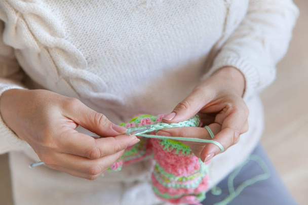 A woman knits a bright colored canvas with spokes. Hands close-u - Foto, Bild