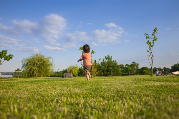 De jongen loopt langs het gras. - Foto, afbeelding
