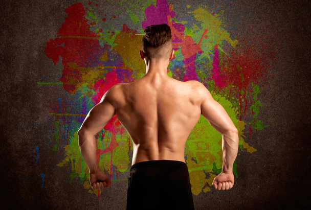 Strong guy with colorful paint wall and weight - Photo, Image