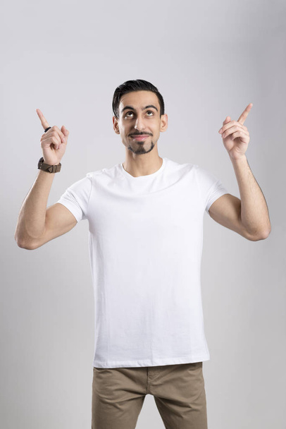 Dark-Haired Young Man in Casual Wear Pointing Fingers Upwards - Photo, Image