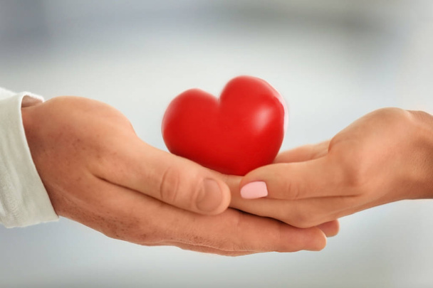 Lovely couple holding small red heart, closeup - Foto, Bild