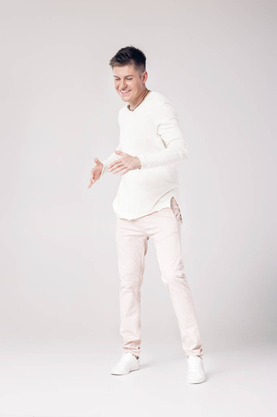handsome young man in a white sweater and pants - Фото, зображення
