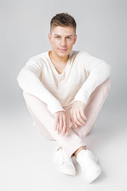 handsome young man in a white sweater - Фото, изображение