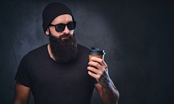 Бородатый мужчина с татуировкой держит чашку кофе
. - Фото, изображение