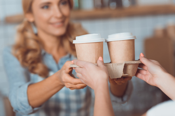 serveerster holding wegwerp koffie kopjes - Foto, afbeelding