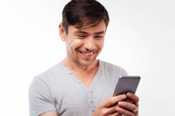 Feliz hombre guapo leyendo mensaje de texto con sonrisa
 - Foto, imagen
