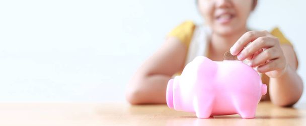 Azjatyckie kobiety wprowadzenie monet pieniędzy w do metafory pink piggy bank sa - Zdjęcie, obraz