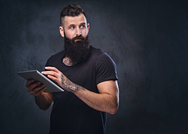 Bearded male holds silver tablet - 写真・画像