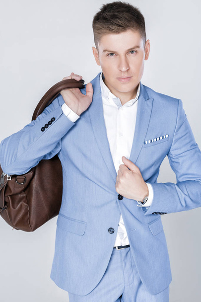 fashion young man in blue suit carrying leather bag - Foto, imagen