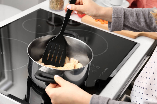 Woman cooking turkey chili on modern stove - Foto, immagini
