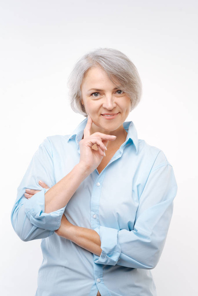 Mulher de cabelos grisalhos tocando bochecha com o dedo
 - Foto, Imagem