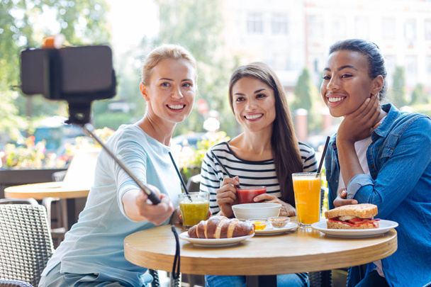 Charming naiset ottavat selfietä monopodin kanssa kahvilassa
 - Valokuva, kuva