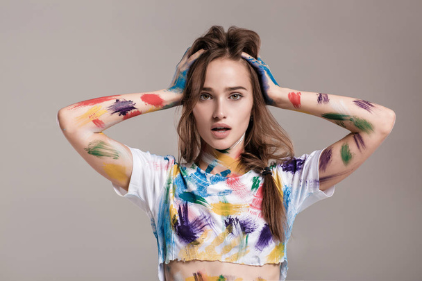 young woman smeared in multicolored paint. - 写真・画像