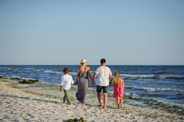 Happy family walks along the seaside holding hands. - Photo, image