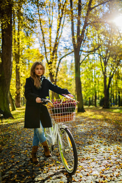 Happy active teenager riding bike in fall autumn park. Young gir - Fotoğraf, Görsel