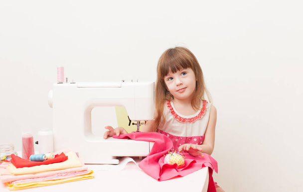 The girl is engaged in needlework using sewing machine - Foto, imagen