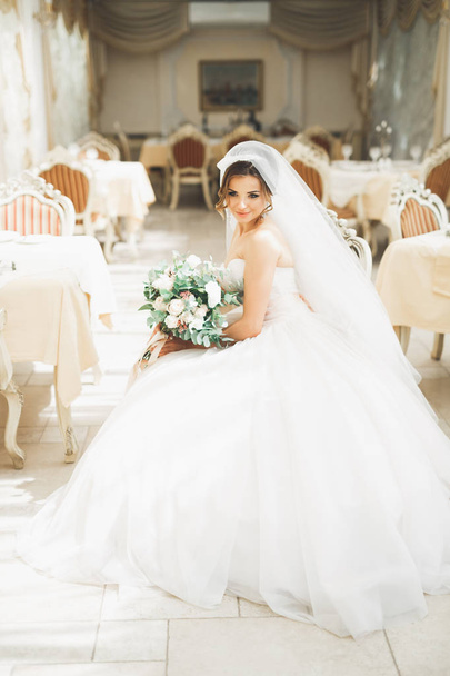 Beautiful bride with wedding bouquet posing in hotel - 写真・画像
