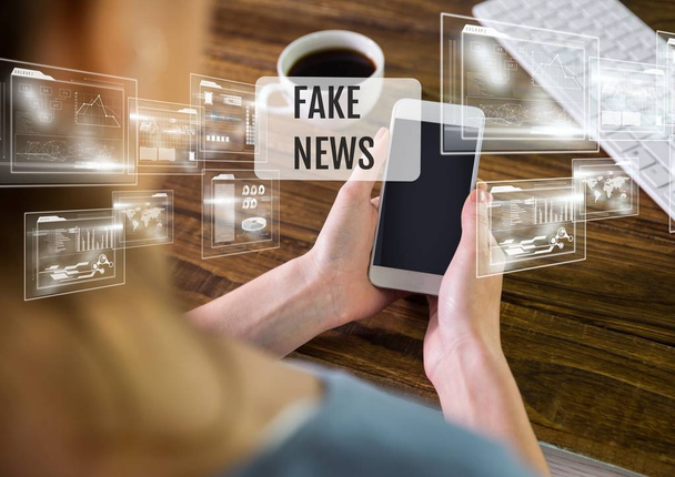 Holding phone with Fake news text - Фото, зображення
