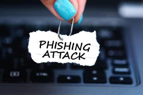 Phishing attack threat with woman hand holding fishing hook against laptop keyboard - Photo, Image