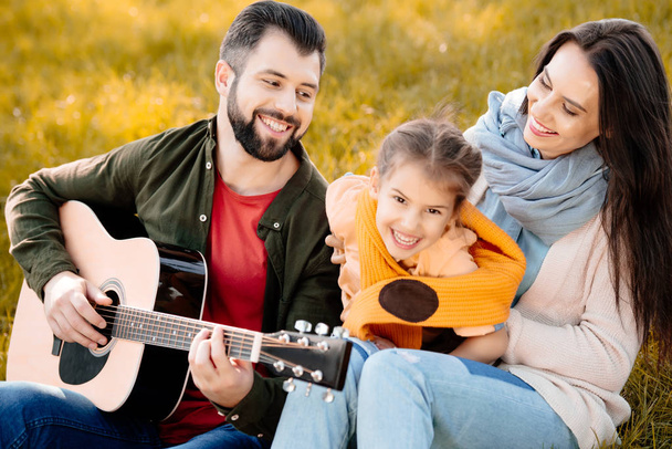 man spelen gitaar met familie - Foto, afbeelding