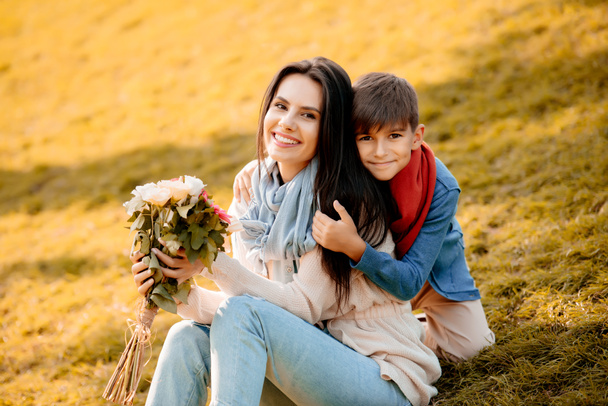 Hijo con madre sosteniendo flores
 - Foto, Imagen